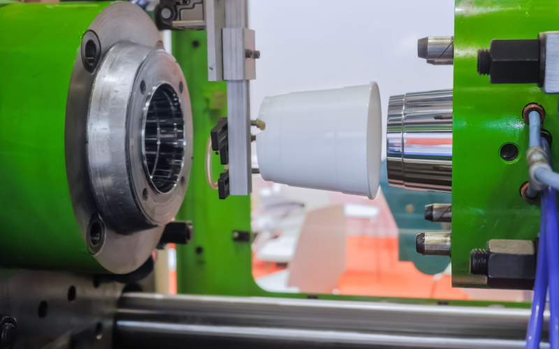 An Injection Moulding machine operating alongside a robotic arm in action.