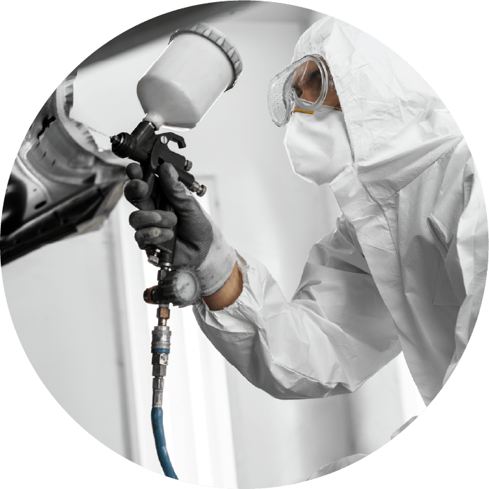 A person is wearing protective clothes to spray paint with a spray gun.