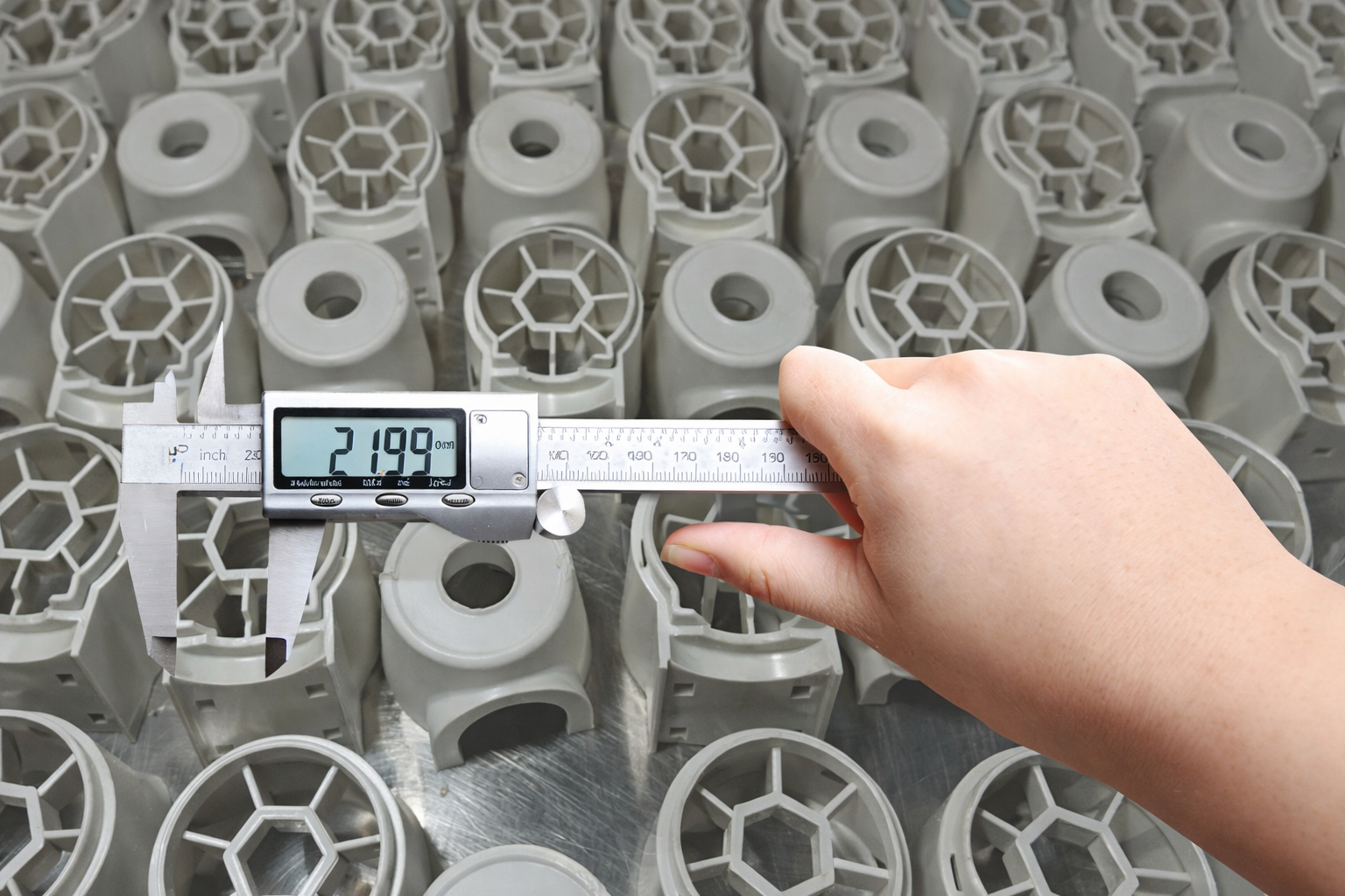 Engineer measuring plastic component dimensions using digital caliper during injection molding tolerance inspection in a plastic injection moulding factory